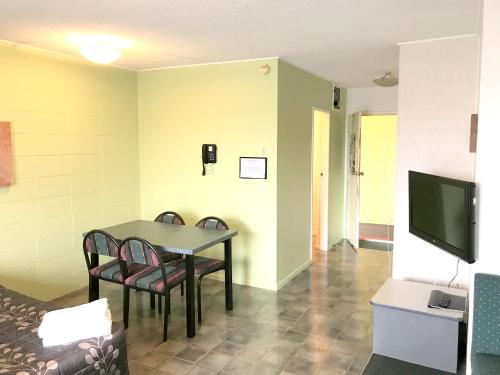 a dining room with a table and chairs and a television at Greenview Motel in Rotorua