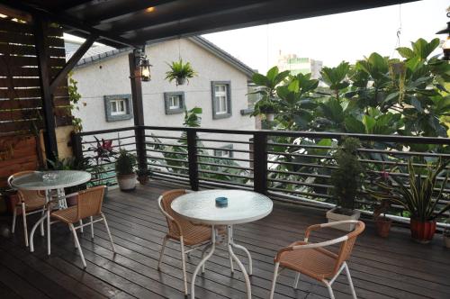 two tables and chairs on a balcony with plants at 青禾溫泉家民宿 in Jiaoxi