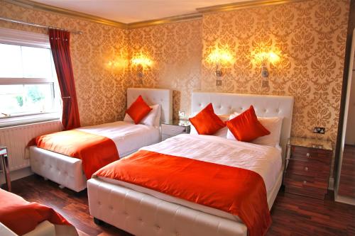 a bedroom with two beds with red pillows at Crompton Guest House in Hounslow