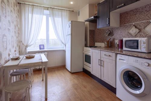 a kitchen with a washer and a table with a microwave at Apartment on Turku in Saint Petersburg