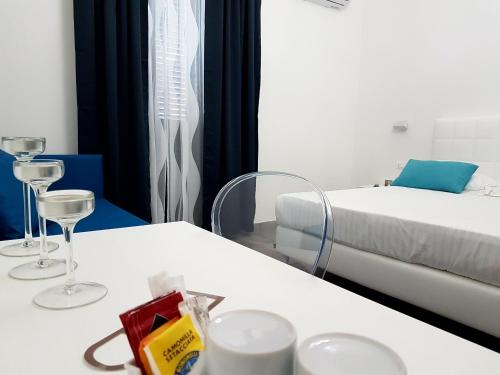 a room with a bed and a white table with glasses at Etna Suite Group in Catania
