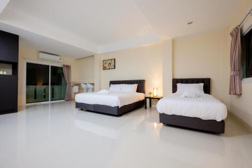 2 łóżka w pokoju z białą podłogą w obiekcie Wisdom Hotel w mieście Samut Songkhram