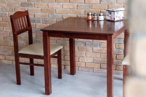 Wisdom Hotel في ساموت سونكرام: طاولة خشبية مع كرسي وجدار من الطوب