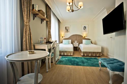 a hotel room with two beds and a table at Villa Blanche Hotel SPA & Garden Pool in Istanbul