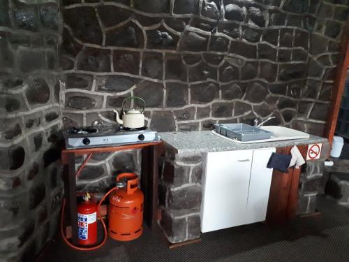 a kitchen with a stove and a stone wall at Amanzi Empilo Bungalow in Rhodes