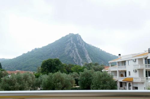 a mountain in the distance with a building and trees at Apart Hotel Forte Roses Montenegro KO Buljarica in Petrovac na Moru