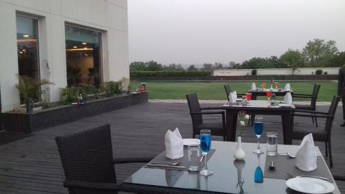 a table with glasses and napkins on a patio at Gurmon Hotels Sohna Road Gurugram, a member of Radisson Individuals in Sohna