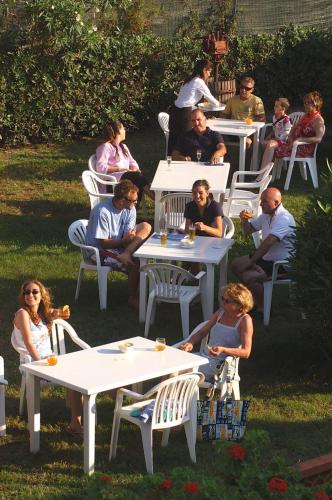 a group of people sitting at tables in a yard at Frank's Hotel in Capoliveri