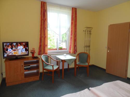 a room with a table and chairs and a television at Pension Bier in Burg