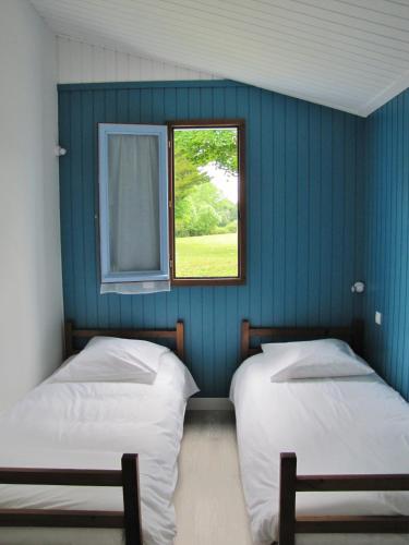 - 2 lits dans une chambre bleue avec fenêtre dans l'établissement Le Hameau de Saintonge, à Tonnay-Boutonne