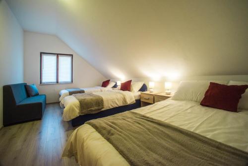 a bedroom with two beds and a chair and a window at Apartments Osijek by the River in Osijek