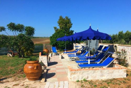 a row of blue lounge chairs and an umbrella at Albadido in Campomarino