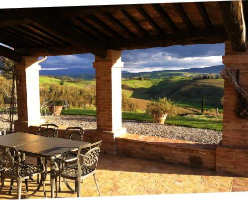 a table and chairs on a patio with a view at Podere Cunina in Buonconvento