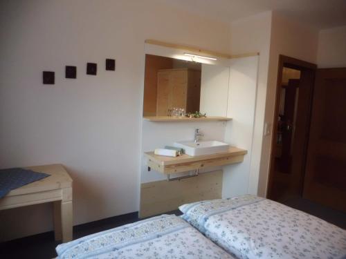 a bathroom with a sink and a bed and a mirror at Haus Rohregger in Mittersill