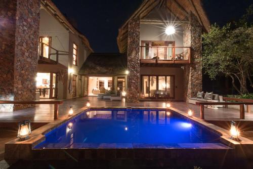 a swimming pool in front of a house at night at eKhaya Bush Lodge in Hoedspruit