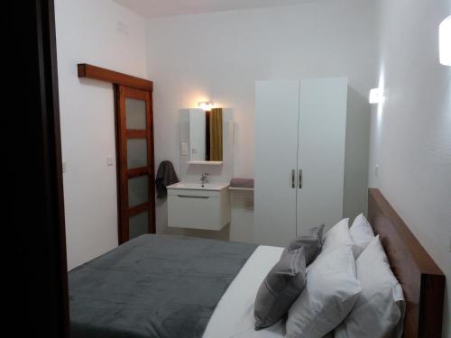 a bedroom with a bed and a bathroom with a sink at Beachfront Deluxe Apartment in Marsalforn