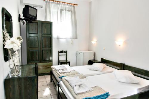 a bedroom with two beds and a tv and a window at Aleka's Rooms in Tinos