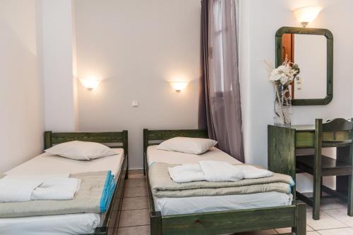 two beds in a room with a mirror and a table at Aleka's Rooms in Tinos