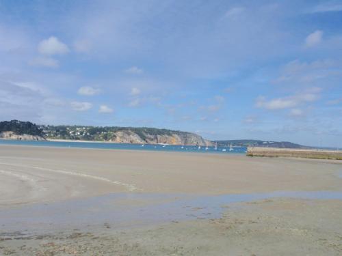 a beach with the ocean and mountains in the background at St Guenole Apartments in Landévennec