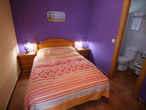a bedroom with purple walls and a bed with two lamps at Albergue de Portilla in Portilla de la Reina