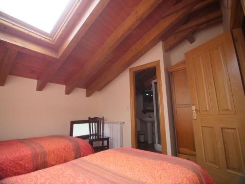 a bedroom with two beds and a wooden ceiling at Albergue de Portilla in Portilla de la Reina