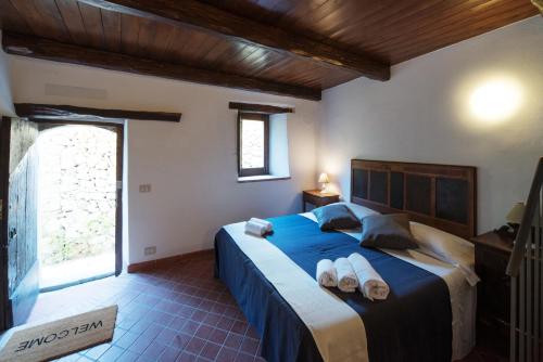 a bedroom with a blue bed with towels on it at The Clock Houses Borgo Gallodoro in Letojanni