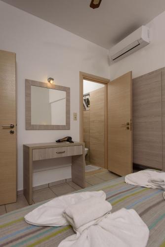 a bathroom with two beds and a sink and a mirror at Nikos Hotel in Matala