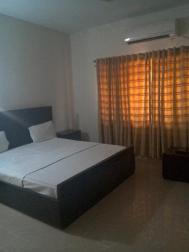 a bedroom with a bed and a window with curtains at Pyramid International Guest House in Islamabad
