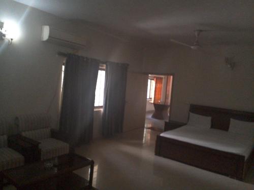 a bedroom with a bed and two chairs and a window at Pyramid International Guest House in Islamabad