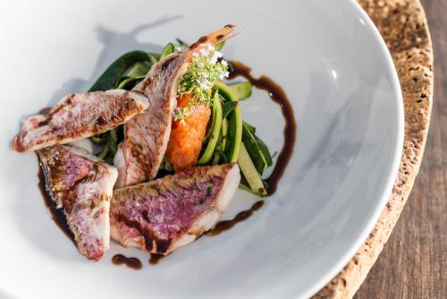 a plate of food with meat and vegetables on a table at Hôtel Le Bailli De Suffren in Rayol-Canadel-sur-Mer