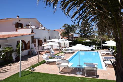 una piscina con sillas y sombrillas junto a un edificio en Villa Blanche Dimora Di Charme, en Marsala