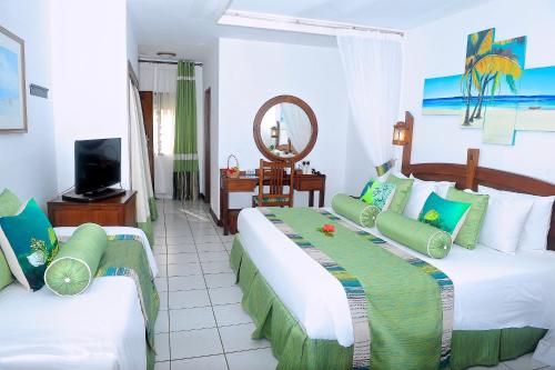 um quarto de hotel com duas camas e uma televisão em Voyager Beach Resort em Mombaça