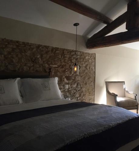 une chambre avec un lit et un mur en pierre dans l'établissement Domaine Les Martins - Gordes, à Gordes