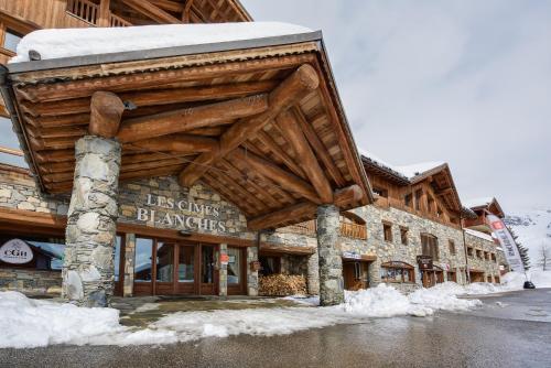 a building with a wooden roof in the snow at CGH Résidences & Spas Les Cimes Blanches in La Rosière