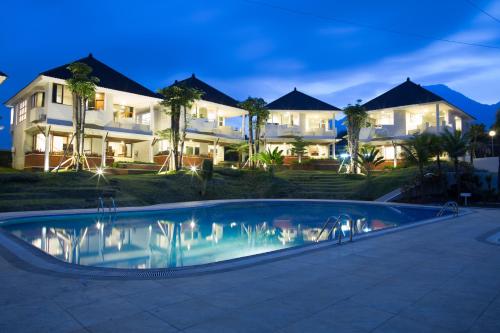 a house with a swimming pool in front of a house at Samara Resort in Batu