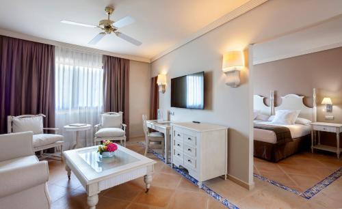 a hotel room with a bed and a living room at Barceló Marbella in Marbella