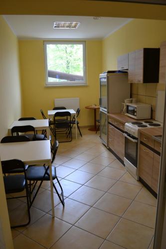uma cozinha com mesas e cadeiras e uma cozinha com um fogão em Hostel Mikołajczyka59 em Sosnowiec
