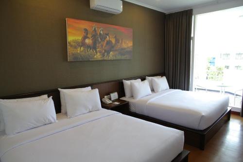 a hotel room with two beds and a painting on the wall at Samara Resort in Batu
