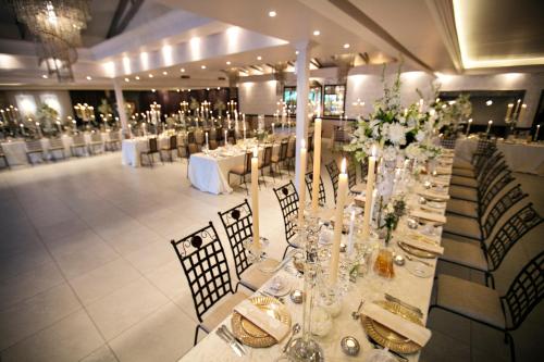 salę bankietową z białymi stołami, krzesłami i kwiatami w obiekcie Oxbow Country Estate w mieście Bronkhorstspruit