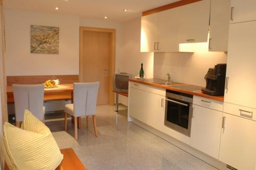 a kitchen with white cabinets and a table with chairs at Hotel Silvretta in Sankt Gallenkirch