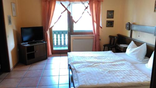 a bedroom with a bed and a television and a window at Landhaus im kühlen Grunde Garni in Pracht