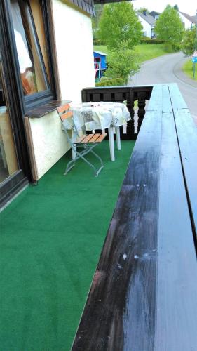 a table and a bench on a porch with green grass at Landhaus im kühlen Grunde Garni in Pracht