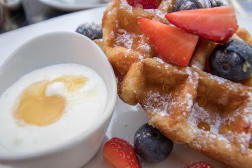 a plate of waffles with fruit and a dollop of yogurt at A Park View Hotel in Wolverhampton