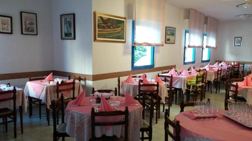 - une salle à manger avec des tables, des chaises et des serviettes roses dans l'établissement Hotel Rosalba, à Riccione