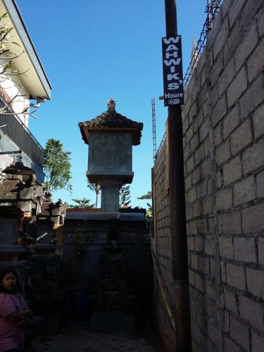 a woman is standing next to a brick wall at Wahwik's House in Ubud