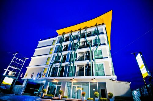 ein hohes weißes Gebäude mit gelbem Oberteil in der Unterkunft The Sila Hotel in Si Racha