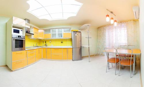 オムスクにあるOmsk Sutki Apartments on 70 let oktyabrya 16/4のキッチン(黄色のキャビネット、テーブル、椅子付)