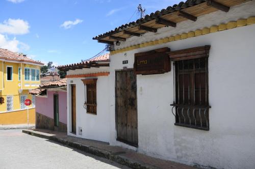 Un edificio blanco con puertas de madera en una calle. en Lima Limon Candelaria Hostel, en Bogotá