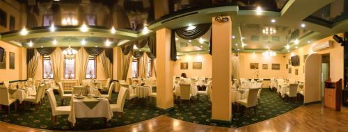 a dining room with white tables and white chairs at Severnye Zori Hotel in Cherepovets