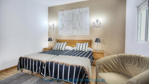 a bedroom with a bed and two chairs in it at Edificio Prieto Vivienda 2D in Puerto del Rosario
